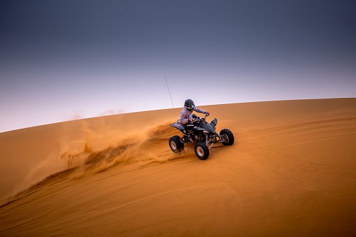 Quad bike crossing a desert dune